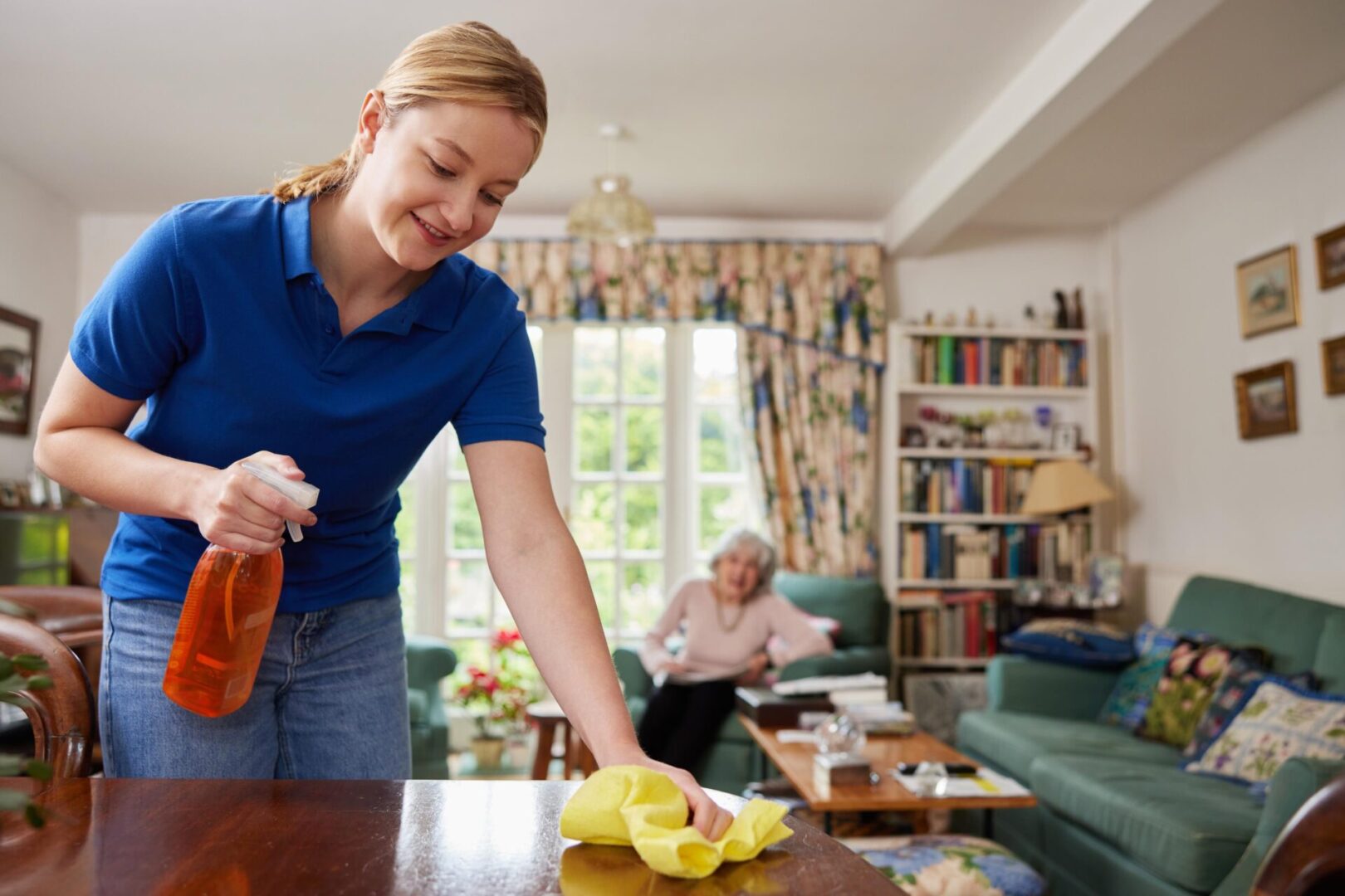 A woman is cleaning the table in her living room.