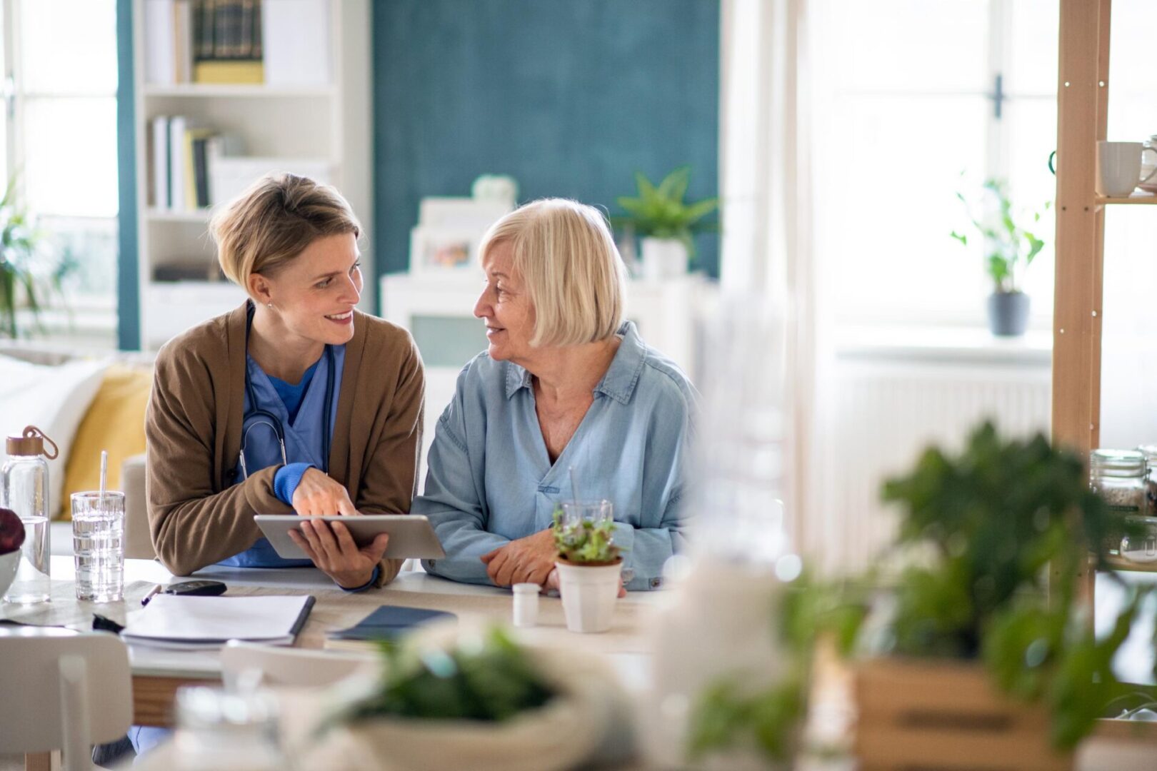 Two women sitting at a table with a tablet.