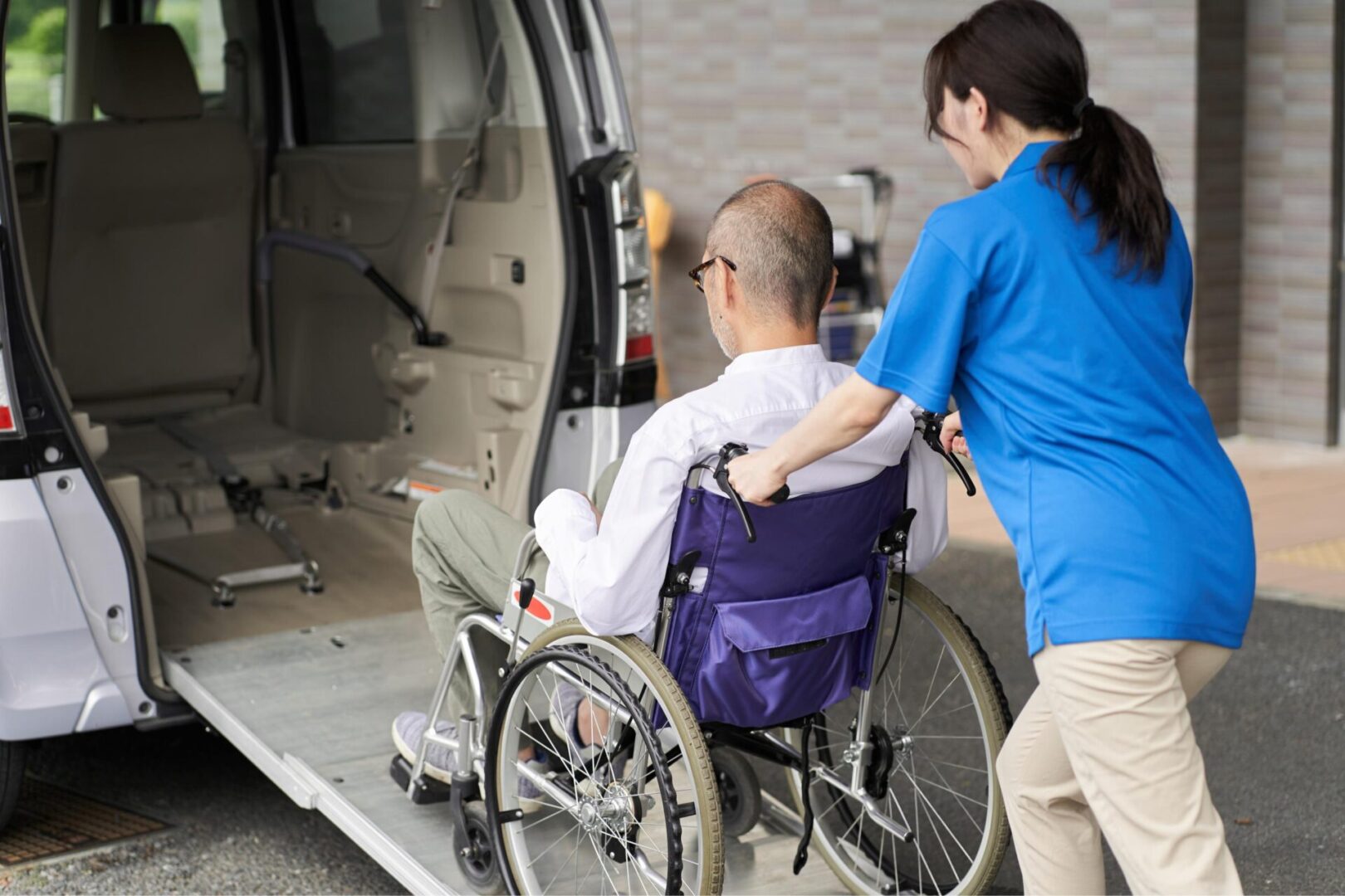 A man in a wheelchair being assisted by a woman.